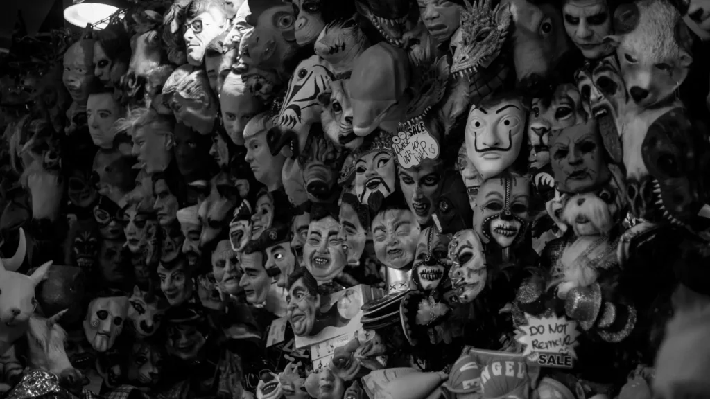 Wand voller unterschiedlicher Masken in Schwarz-Weiß – Symbol für Masking, soziale Überanpassung und den Verlust des authentischen Selbst bei neurodivergenten Menschen.