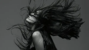 Schwarz-Weiß-Porträt einer Frau mit wehendem Haar, Symbol für Identitätsverlust, Hochsensibilität und die innere Zerrissenheit von Empathen bei Trauma und Anpassung.