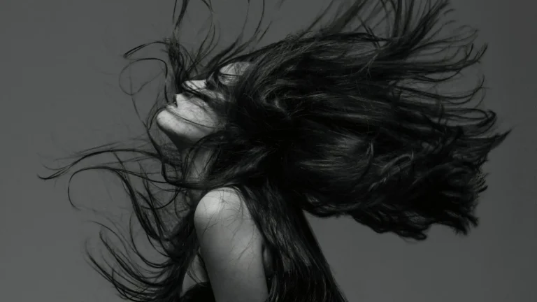 Schwarz-Weiß-Porträt einer Frau mit wehendem Haar, Symbol für Identitätsverlust, Hochsensibilität und die innere Zerrissenheit von Empathen bei Trauma und Anpassung.