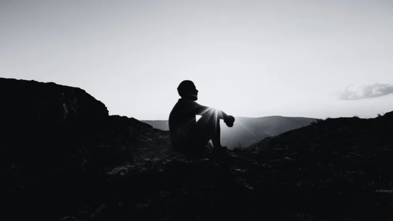 Silhouette einer sitzenden Person in der Natur bei Sonnenaufgang – Symbolbild für Trauma, innere Einkehr, Heilungsweg und Nervensystem-Regulation.